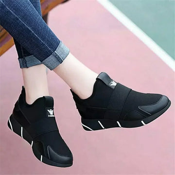 Black slip-on sneakers with elastic straps and white sole accents, casual streetwear style