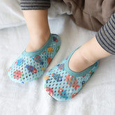 Baby wearing light blue mesh slip-on socks with colorful fish print, soft fabric, snug fit