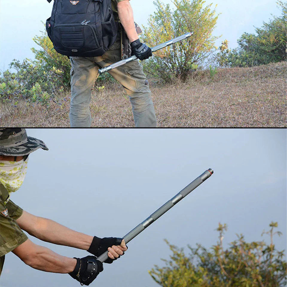 Man in outdoor tactical streetwear, olive cargo pants, gloves, and camo hat holding a metallic staff
