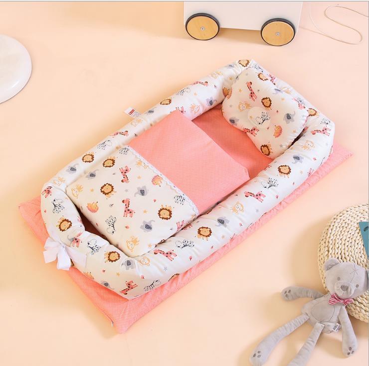 Soft cotton baby nest with animal print, pastel pink bedding, and plush pillow on a peach background.
