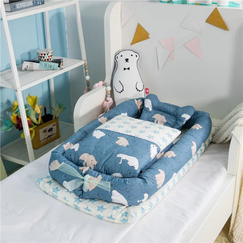 Blue cotton baby nest with polar bear print, matching pillow, and soft padded sides on bed
