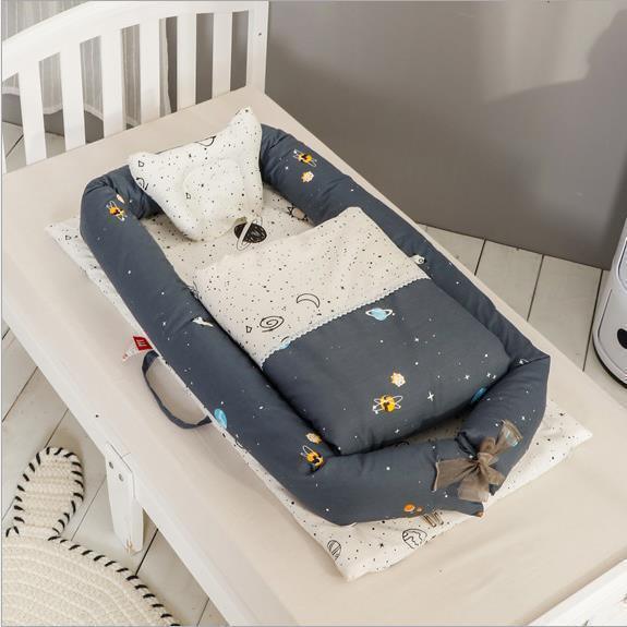 Soft baby nest in blue and white cotton with space-themed print, cozy padded fit, crib setting