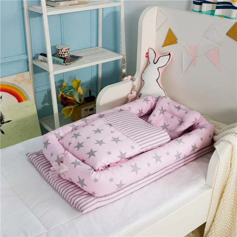 Pink baby bedding set with grey star pattern and striped pillow on a toddler bed