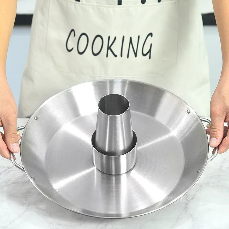 Person wearing a beige apron holding a stainless steel roasting pan with cone center
