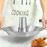 Person in light apron holding stainless steel vertical roasting pan for chicken on marble counter