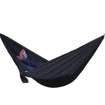 Person relaxing in a black oversized streetwear hoodie and pants in a dark hammock.