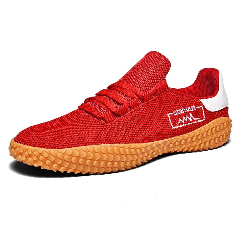 Red mesh athletic sneaker with textured tan sole, low-top design, and white heel accent