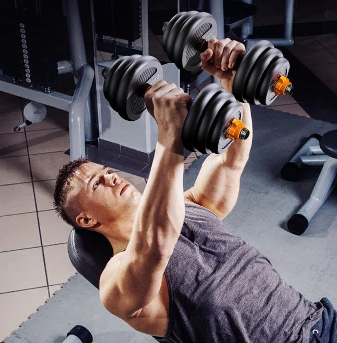Man in fitted grey athletic tank top lifting black adjustable dumbbells on gym bench