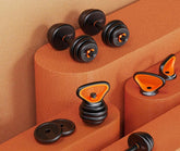 Adjustable black and orange dumbbells and kettlebells with sleek, modern design on textured surface.