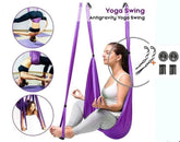 Woman using a purple antigravity yoga swing hammock, soft fabric, relaxed fit, indoor setting