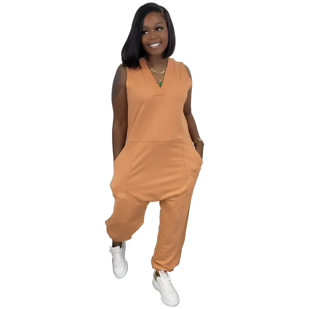 Woman in sleeveless orange jumpsuit with relaxed fit and side pockets, wearing white sneakers