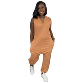 Woman in sleeveless orange jumpsuit with relaxed fit and side pockets, wearing white sneakers