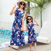 Matching blue and white sleeveless leaf print summer dresses, relaxed fit, worn by woman and girl outdoors