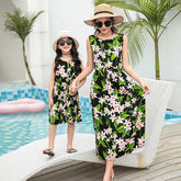 Mother and daughter in matching sleeveless black floral dresses, relaxed fit, poolside.