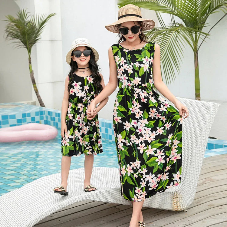 Mother and daughter in matching sleeveless black floral dresses, relaxed fit, poolside.