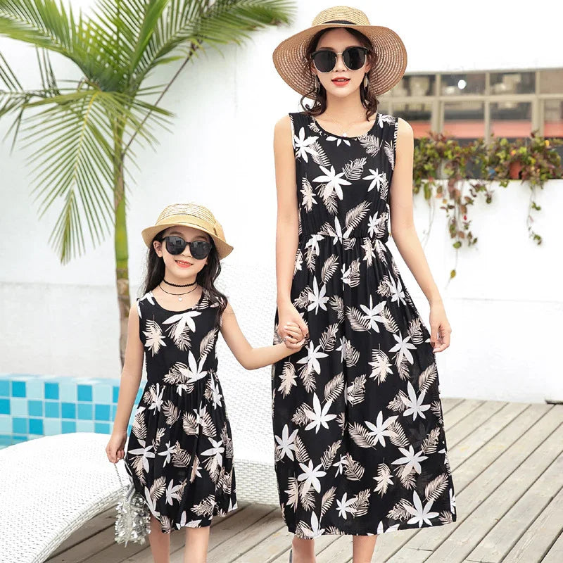 Mother and daughter wearing matching sleeveless black floral print summer dresses with relaxed fit
