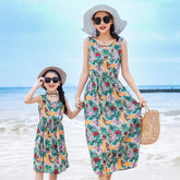Mother and daughter in sleeveless floral summer dresses with tropical print and relaxed fit on the beach