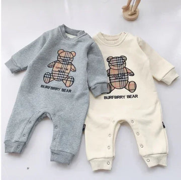 Two long-sleeve baby jumpsuits in grey and cream, with plaid teddy bear prints and snap buttons.