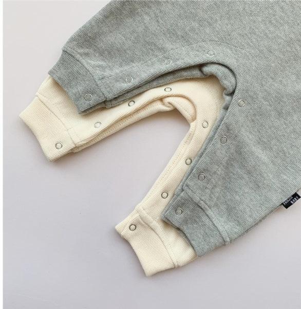 Soft knit baby rompers in light grey and cream, featuring ribbed cuffs and snap closures