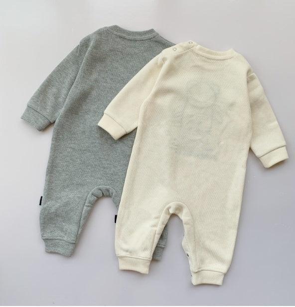 Two long sleeve baby jumpsuits in soft ribbed knit, one grey and one cream, relaxed fit