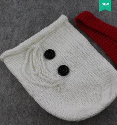 Knit white crossbody bag with black button accents and a thick red strap on gray background