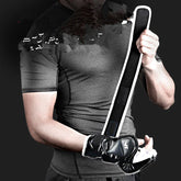Man in fitted grey short sleeve athletic shirt with black training gloves holding padded strap
