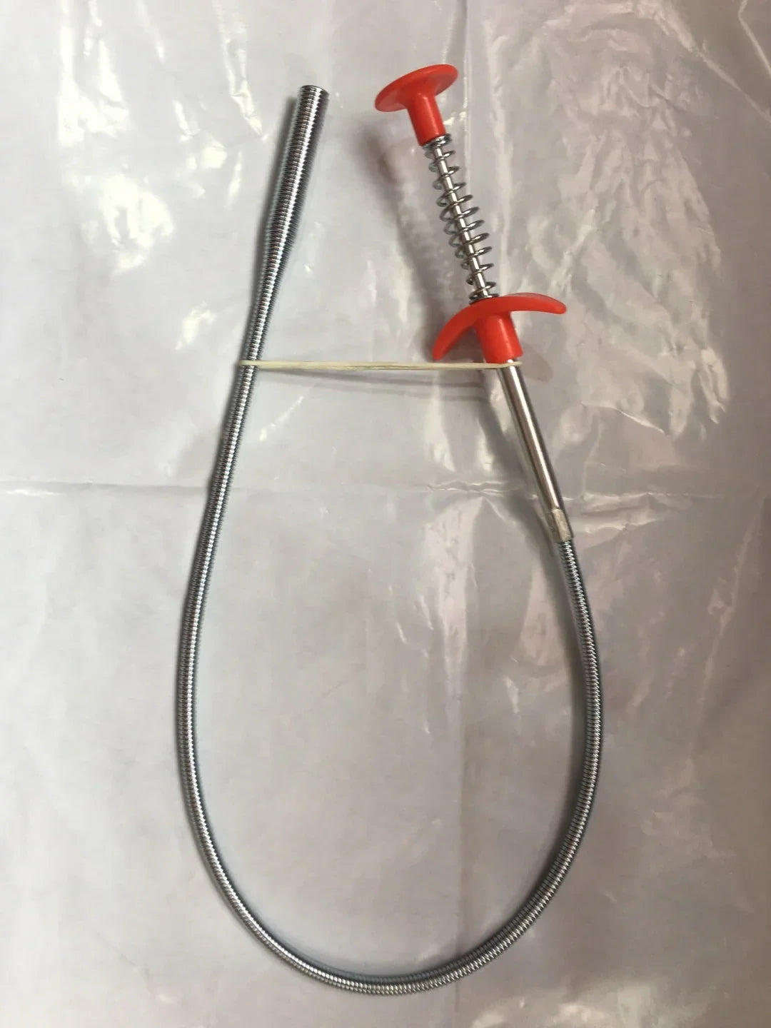 Flexible metal grabber tool with red plastic handle and spring-loaded claws