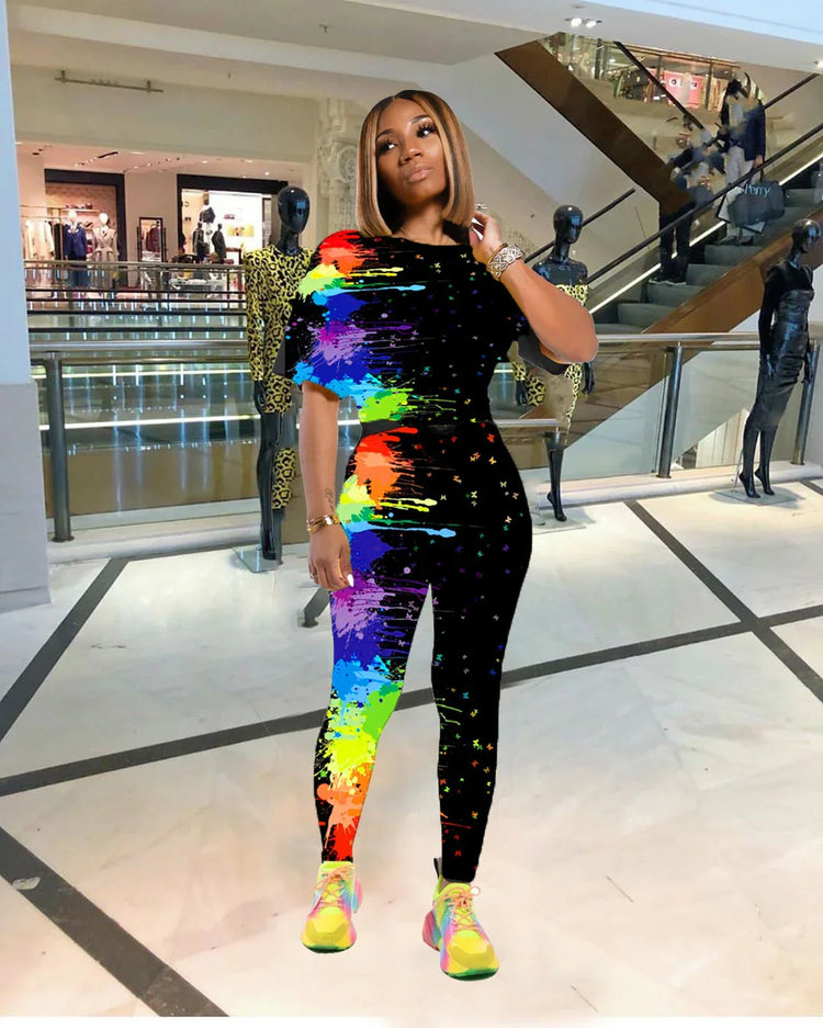 Woman wearing a fitted black jumpsuit with vibrant rainbow paint splatter print in a mall setting