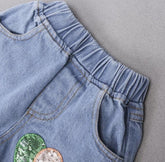 Light blue denim shorts with elastic waist, side pockets, and sequin patch detail