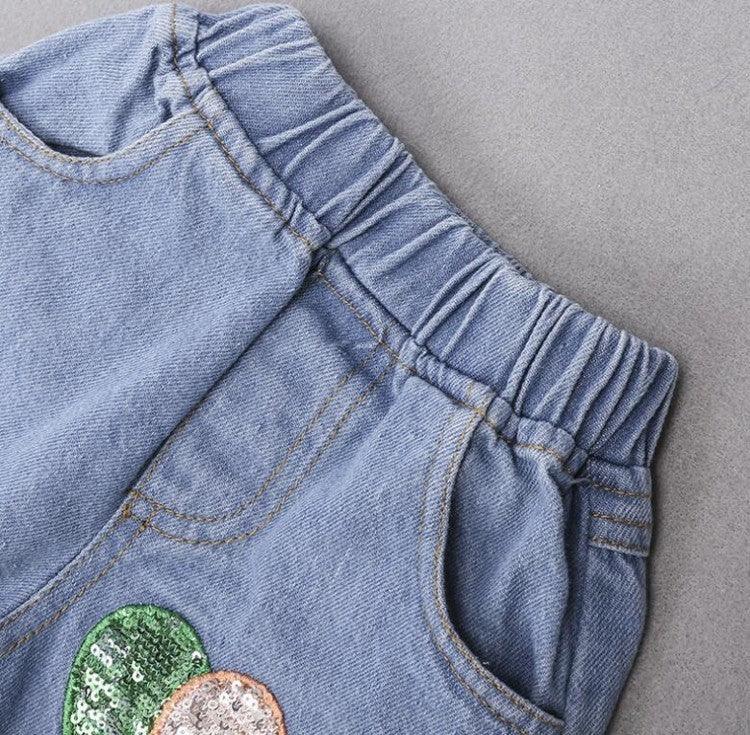 Light blue denim shorts with elastic waist, side pockets, and sequin patch detail