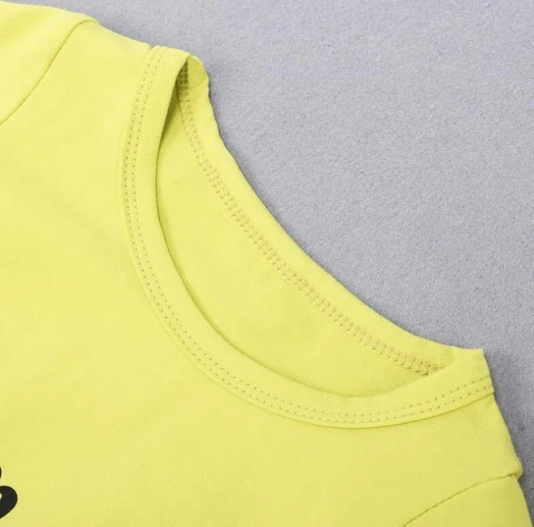 Close-up of yellow cotton crew neck t-shirt with double-stitched collar on gray background.