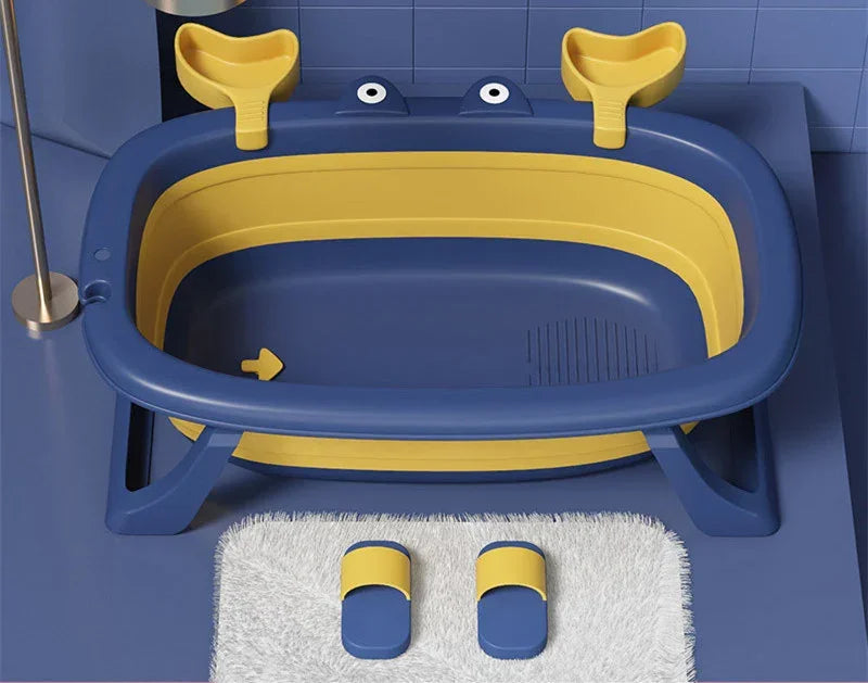 Blue and yellow plastic baby bathtub with matching slippers on white rug, modern bathroom setting