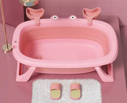 Pink collapsible plastic bathtub with cartoon eyes, matching pink slippers, and a white rug