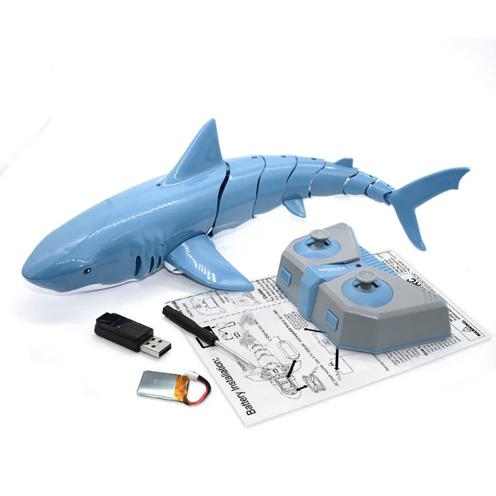 Blue plastic remote control shark toy with grey controller, charger and instructions on white background