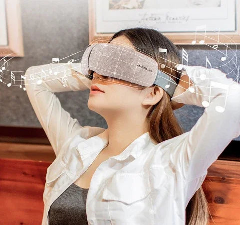 Woman wearing a grey padded eye mask and white button-up shirt in relaxed pose, indoor setting.