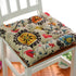 Colorful floral-patterned cotton chair cushion with a soft, tufted design on a white chair