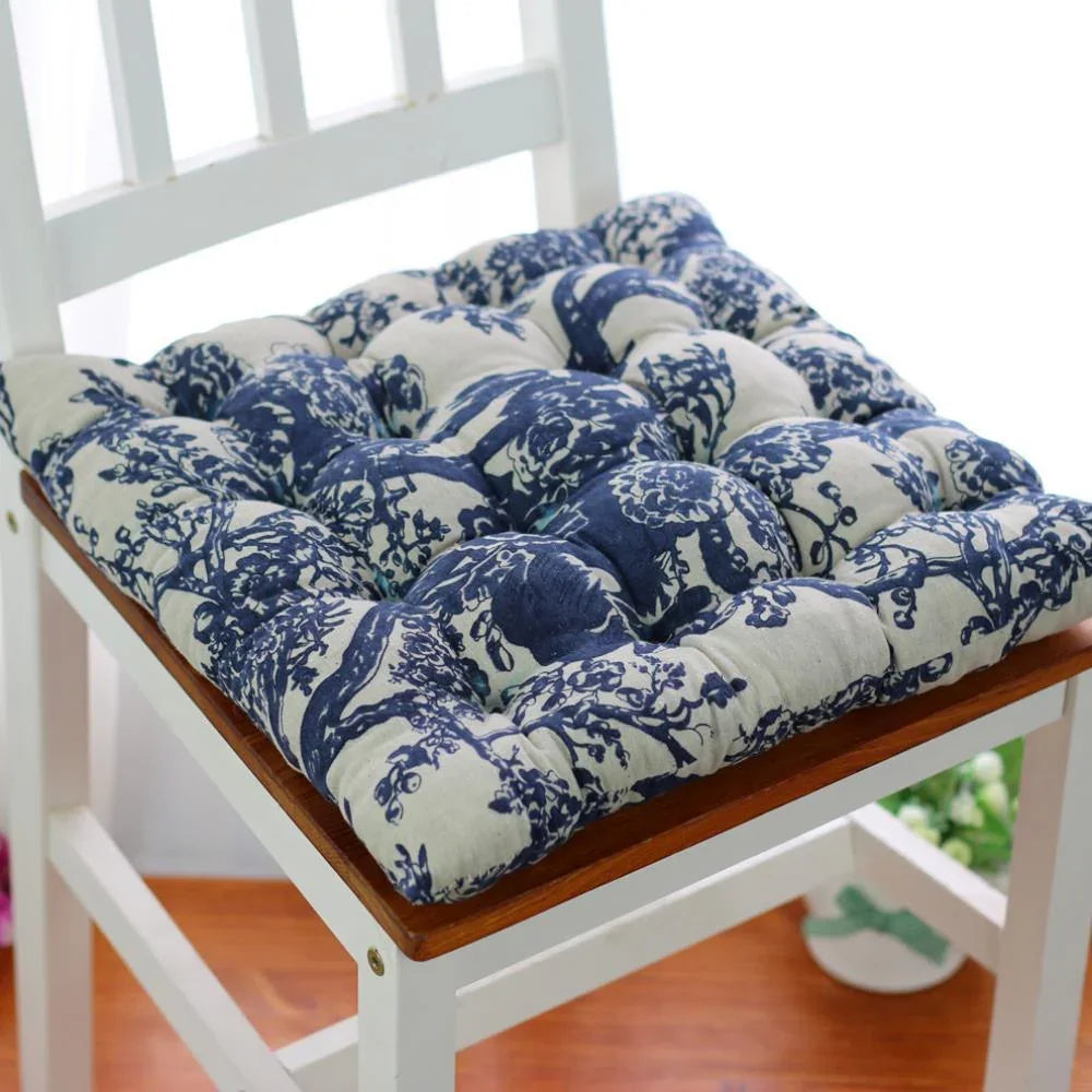 Blue and white floral cotton chair cushion with plush, tufted design on a wooden chair