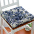 Blue and white floral cotton cushion with tufted design on a wooden chair