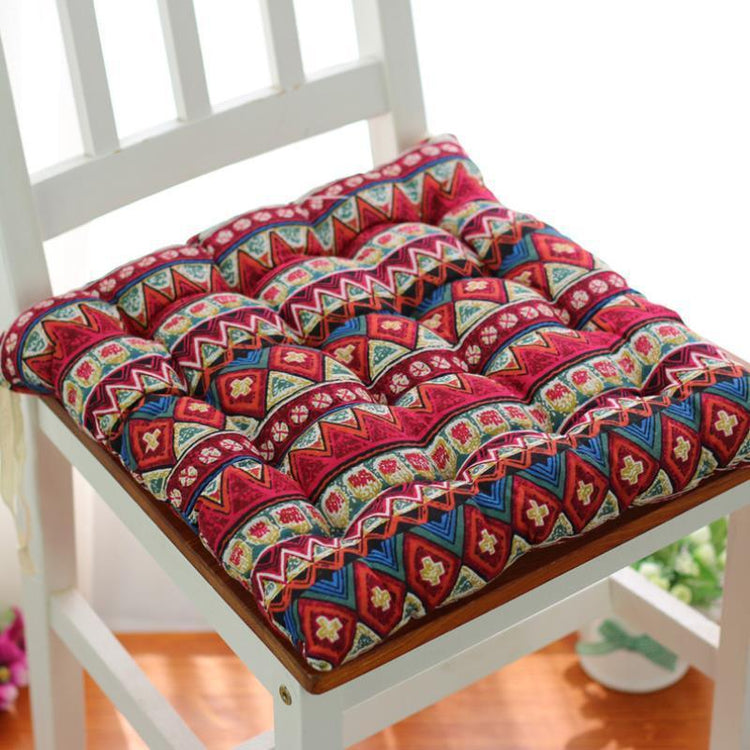 Colorful geometric patterned cotton chair cushion with plush, tufted design on a wooden chair