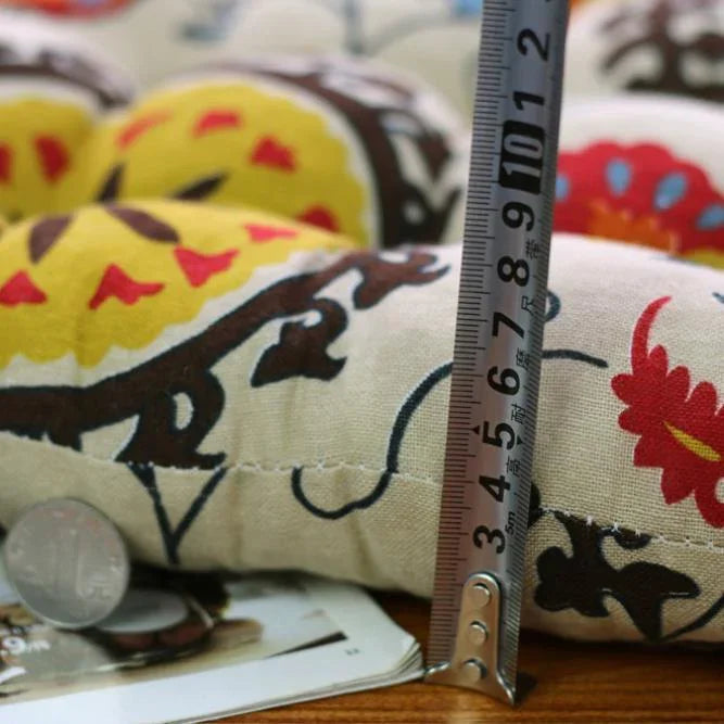 Close-up of colorful embroidered cotton cushion with measuring ruler and coins for scale