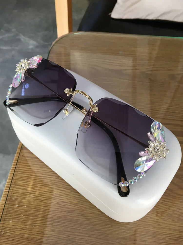 Oversized rimless sunglasses with purple gradient lenses, crystal embellishments, and gold bridge