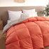 Modern bedroom with orange and gray quilted comforter, soft bedding, and decorative pillows