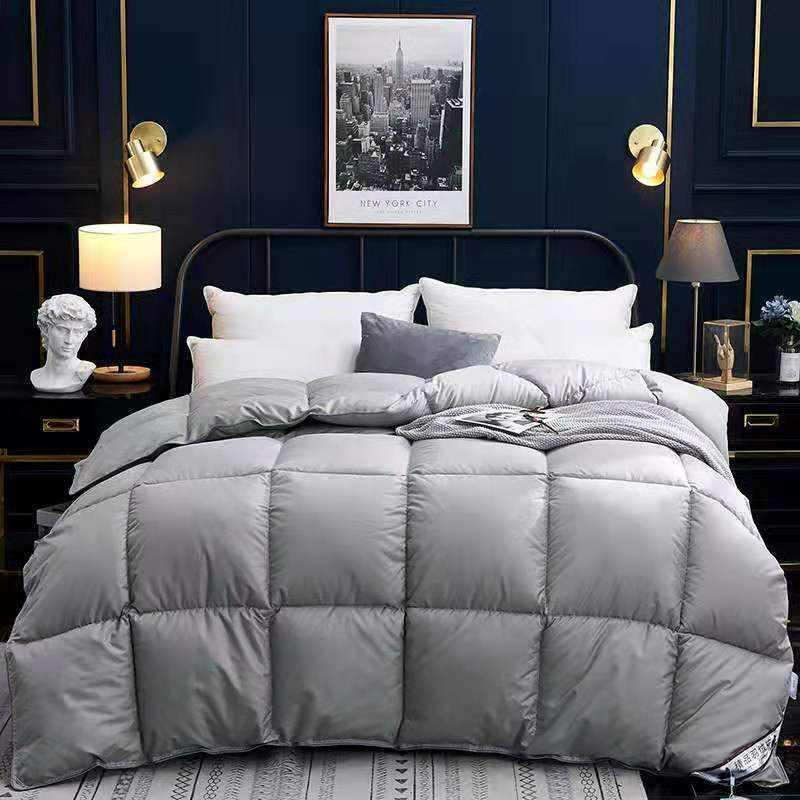 Modern bedroom with a large gray quilted comforter, soft pillows, and cozy bedding.