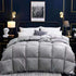 Modern bedroom with a large gray quilted comforter, soft pillows, and cozy bedding.