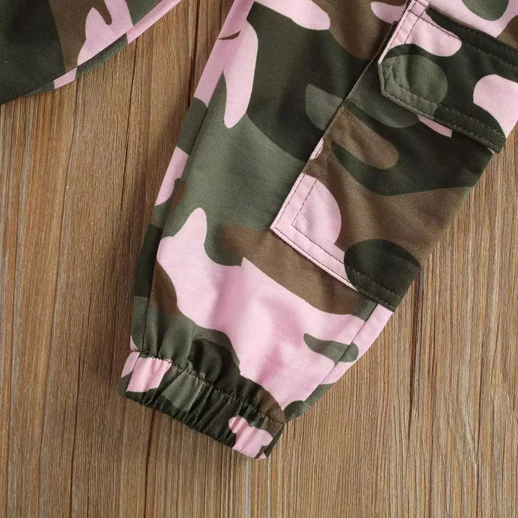 Pink and green camo cargo pants with elastic cuffs and pocket detail on wood surface