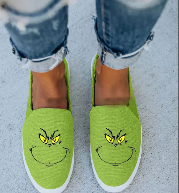 Green canvas slip-on shoes with cartoon face print, paired with distressed denim jeans.