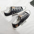 Black canvas low-top sneakers with white soles, grey laces, and bear patch detail.