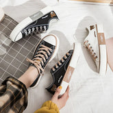 Black and white low-top canvas sneakers with bear embroidery, beige laces, and contrasting soles