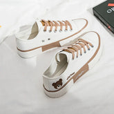 White canvas sneakers with beige laces, bear embroidery, and chunky rubber sole