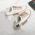 White canvas low-top sneakers with tan accents, flat laces, and embroidered bear detail.